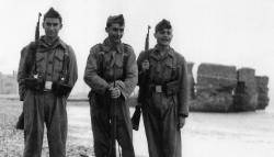 Imatge dels anys '40 del segle XX on tres soldats es fan una fotografia davant del parapet del Camp de la Bota (a la imatge mig inundat pel mar, actualment està sota les aigües del port esportiu de Sant Adrià) on es va afusellar a 1.700 persones.
