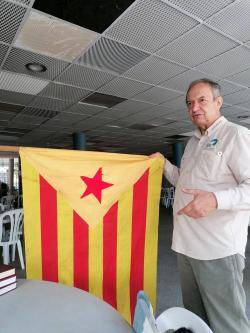 Joan Miquel Touron amb una estelada vermella de més de 50 anys d'antiguitat (una de les primeres estelades vermelles que van existir) al "tendal" del bar del Lycée Charles Renouvier. (19/8/2024)